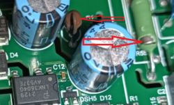 Zbliżenie na elementy elektroniczne na zielonej płytce PCB z zaznaczonymi kondensatorami elektrolitycznymi i ceramicznym.