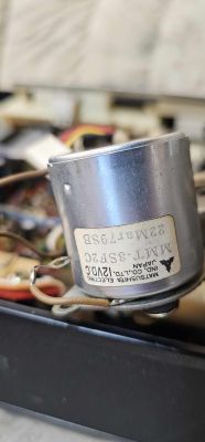 Silnik magnetofonu Matsushita MMT-8SF2C 12V DC Zbliżenie na silnik magnetofonu Matsushita MMT-8SF2C 12V DC w radiomagnetofonie, pokazujący etykietę modelu.
