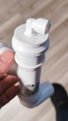 Białe plastikowe przyłącze wężyka 6 mm zamontowane w korku rury 32 mm