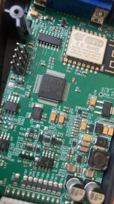 Zbliżenie na płytkę elektroniczną z widocznymi układami scalonymi i modułem Wi-Fi.