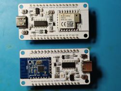 Two microcontroller boards on a blue surface, with USB-C ports and wireless modules