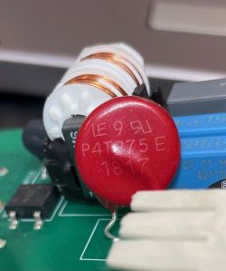 Czerwony warystor oznaczony jako P4T375E na zielonej płytce PCB pieca gazowego