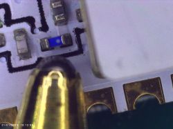 Szczegółowe zbliżenie elementu elektronicznego na płytce drukowanej pod mikroskopem.