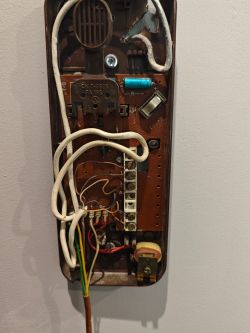 Zbliżenie na stary domofon marki Tesla z otwartą obudową, ukazujące wewnętrzne okablowanie.