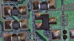 Zbliżenie fragmentu płytki PCB z elementami SMD, w tym rezystorami i diodą.