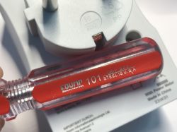 Red Count 101 screwdriver next to an electrical plug adapter