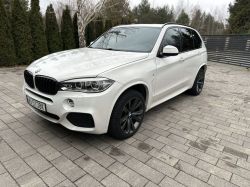 White BMW X5 car parked on a paved driveway.