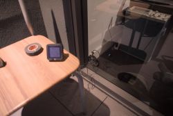 Table with an electronic device and tape, next to a window with cables inside.
