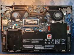 Wnętrze laptopa z widoczną płytą główną, dwoma wentylatorami i baterią.