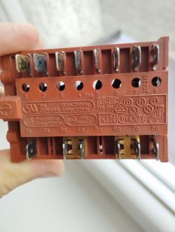 Czerwony przełącznik elektryczny z wygrawerowanymi oznaczeniami technicznymi.