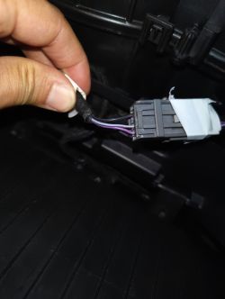 Osoba trzymająca wiązkę przewodów z wtyczką w samochodzie.