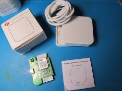 ZigBee Wireless Gateway with packaging, circuit board, and manual on a blue surface.