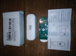 Cozylife Hygrometer with Circuit Board and Manual The image shows a set including a white Cozylife hygrometer, its circuit board, and a user manual placed on a wooden table.