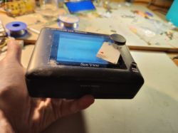 Osoba trzymająca mały, czarny monitor TFT LCD z widoczną naklejką na ekranie.