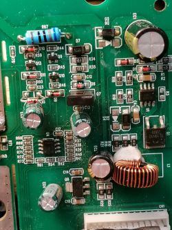 Zbliżenie płytki PCB z elementami SMD, cewką miedzianą i kondensatorami; widoczne oznaczenia D12 i R59