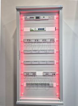 Control cabinet with electrical modules on DIN rails and red LED strip lighting.