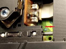 Zbliżenie na mechanizm lasera w urządzeniu SONY z widocznymi zębatkami i sprężyną.