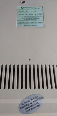 Tabliczka znamionowa i plomba gwarancyjna na spodzie obudowy Commodore C128.