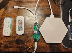 Remote with three buttons, a Wi‑Fi QR code module, and a wired circuit board next to a white hexagonal panel