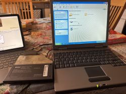 Stary laptop Dell ze stacją dyskietek FDD na stole obok tabletu.