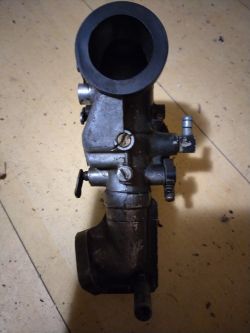 Gaźnik do silnika Briggs 8hp leżący na podłodze.