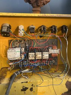 Widok wnętrza szafy elektrycznej z wieloma przewodami i stycznikami.