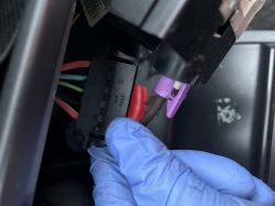 Zbliżenie na wtyczkę elektryczną trzymaną w niebieskiej rękawiczce.