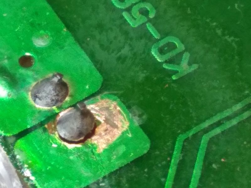 Zbliżenie na uszkodzone pole lutownicze na płytce drukowanej.