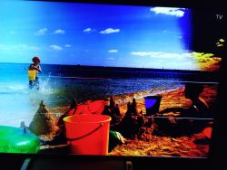 Ekran telewizora z wyraźnymi zniekształceniami kolorów obrazu na plaży.