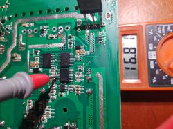 A red multimeter probe touching a circuit board next to a multimeter display showing 16.81 V.