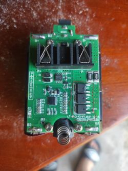 Płytka PCB od BMS z zaznaczonym obszarem wokół tranzystorów MOSFET na tle drewnianym