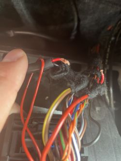 Zbliżenie na wiązkę przewodów elektrycznych z widocznymi czerwonymi przewodami.