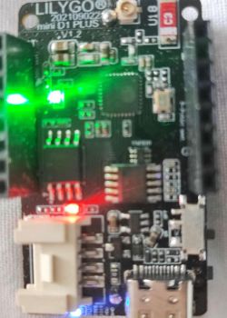 Close-up of LILYGO mini D1 PLUS V1.2 electronic board with lit LEDs.