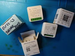 Several WiFi smart switch modules and a box labeled ESP32-C3 Secure Boot lying on a blue surface.