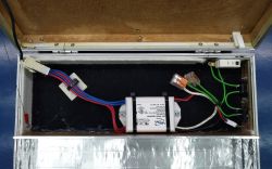 Wnętrze walizki z elektrycznymi komponentami, w tym przetwornicą i przewodami.