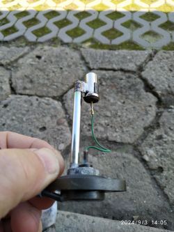 Zbliżenie na czujnik paliwa motocykla z metalowym uchwytem, dwoma przewodami i rezystorem.