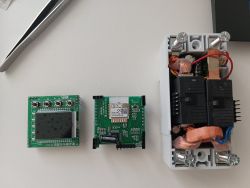 Electronics on a desk: two green PCBs and an open relay module with thick copper wires and screw terminals