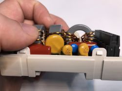 Zbliżenie na wnętrze urządzenia elektronicznego, widoczne komponenty: kondensatory, cewki, złącza.