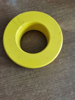 Żółty pierścień metalowy leżący na brązowym blacie stołu.