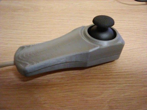 Drukowany w 3D joystick na drewnianym blacie.