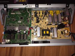 Widok wnętrza zasilacza komputerowego z widocznymi podzespołami elektronicznymi.