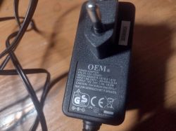 Zasilacz OEM z etykietą techniczną na drewnianej powierzchni.