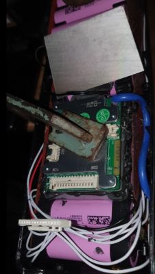 Bateria z ogniwami 18650 i elektroniką BMS, nad którą umieszczono radiator oraz narzędzie do dopasowania części.