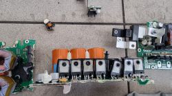 Rozebrane elementy ładowarki OBC z samochodu elektrycznego na podłożu.
