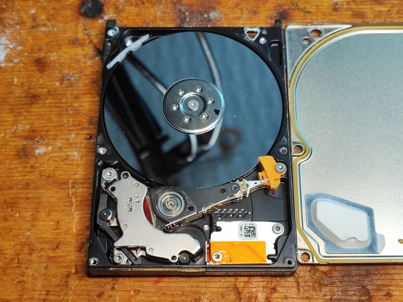 Interior of a Seagate Hard Drive Interior of an opened Seagate hard drive with exposed platter and head arm on a wooden table.