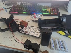 Rozłożona chińska latarka LED UV z modyfikowanym systemem zasilania i akumulatorami AA na biurku.