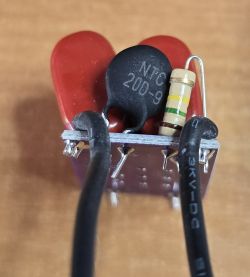 Close-up of electronic components on a circuit board, including an NTC thermistor, a resistor, and capacitors.