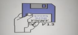 Bild mit einer grafischen Diskette, die mit Amiga Workbench V1.3 beschriftet ist und von einer Hand gehalten wird.