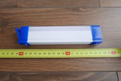 Niebiesko-biała lampa z Aliexpress o długości około 15 cm na tle drewnianych paneli, z miarą w centymetrach.