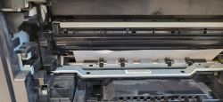 Papier zacięty w drukarce HP LaserJet Pro 200 M276nw widoczny wewnątrz mechanizmu pobierania.